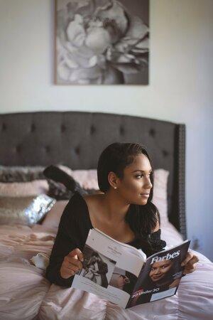 Black Woman Lying On The Bed While Reading Forbes Magazine